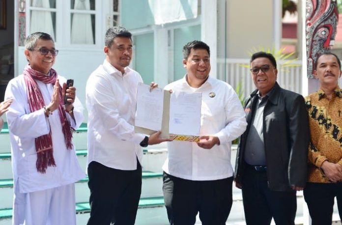 Text Foto :  Gubernur Sumatera Utara (Sumut) Muhammad Bobby Afif Nasution menyerahkan aset Pemerintah Provinsi (Pemprov) kepada Bupati Kabupaten Samosir Vandiko Gultom berupa bangunan yang selama 21 tahun digunakan sebagai Rumah Dinas Bupati, di Pangururan, Samosir, Minggu (6/7/2025). (Foto : Ist)  Istimewa